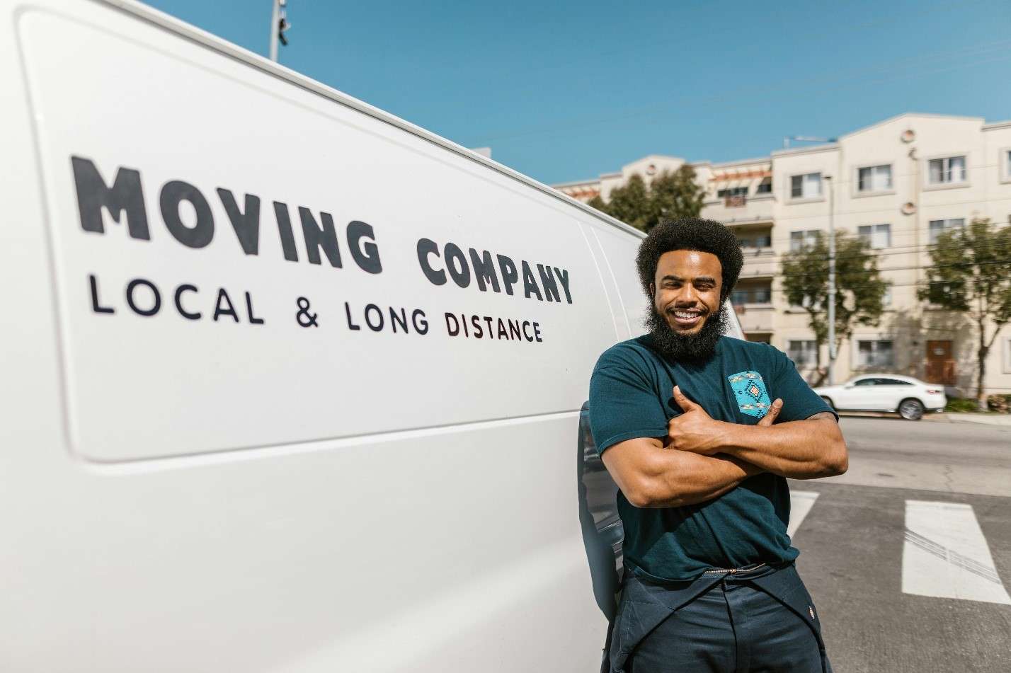 A Confident Male Mover Stands Next to a White Moving Van
