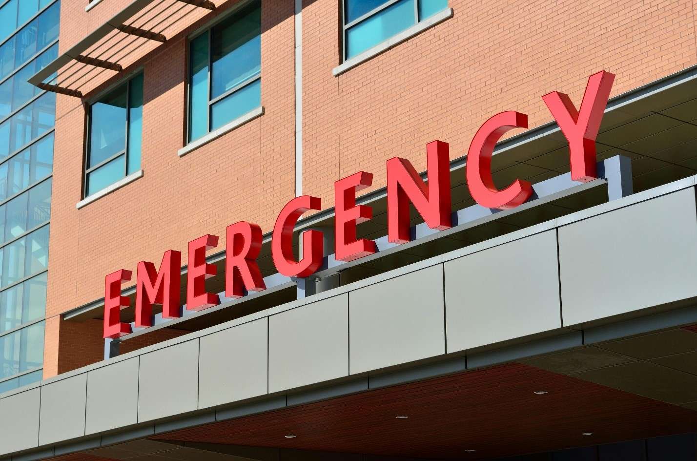 The Bold Red 'Emergency' Sign Prominently Displayed on the Overhang of a Modern Hospital Building
