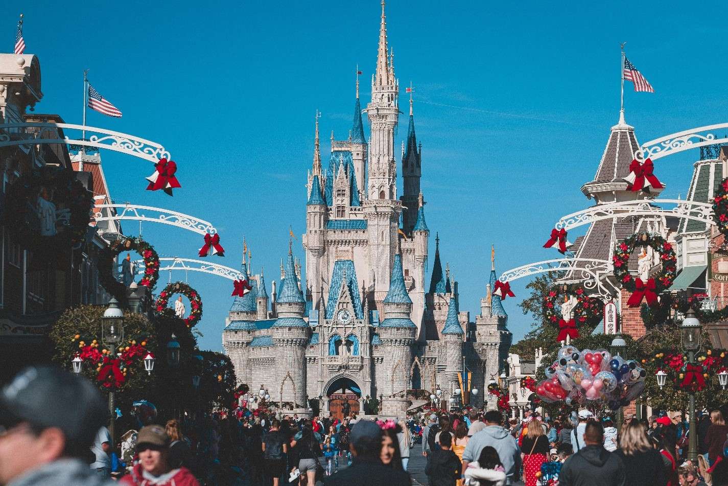 A Bustling Scene Showcasing the Iconic Cinderella Castle Decorated with Festive Wreaths and Red Bows