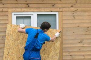 Our worker securing a wooden board over a window to protect the home from potential hurricane damage