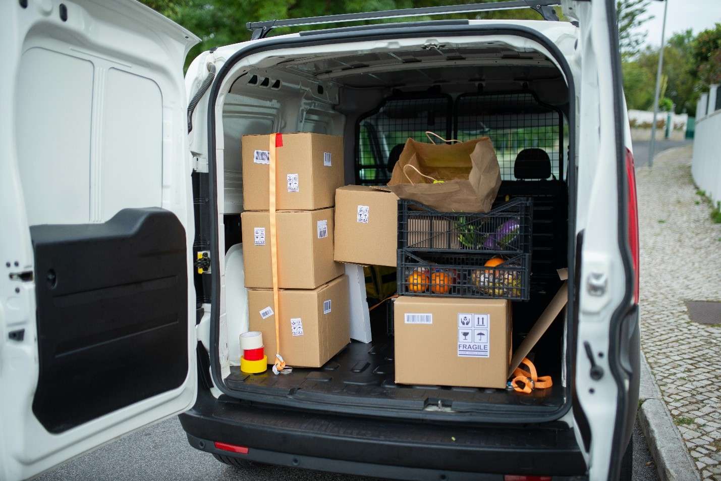 The Back of an Open White Cargo Van, Neatly Packed with Various Labeled Cardboard Boxes and Essential Moving Supplies